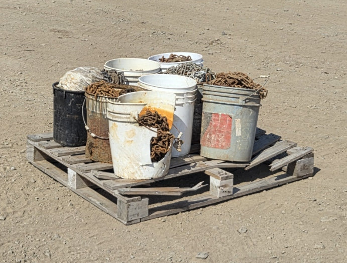 : Side angle showing a heavily cracked white plastic bucket exposing the rusted chain links inside