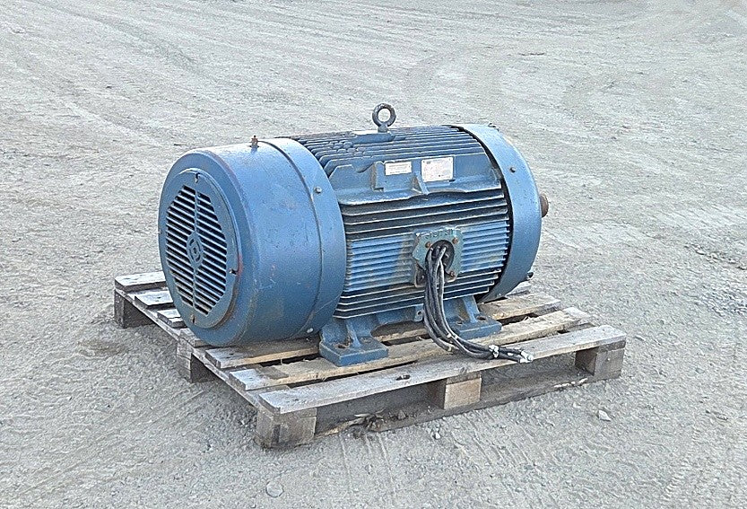 Front angle view of the large blue Siemens 200 HP electric motor on a pallet showing the ribbed cast iron body and cut power cables.