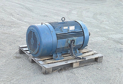 Front angle view of the large blue Siemens 200 HP electric motor on a pallet showing the ribbed cast iron body and cut power cables.