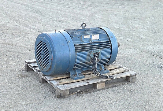 Front angle view of the large blue Siemens 200 HP electric motor on a pallet showing the ribbed cast iron body and cut power cables.