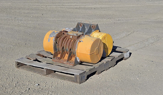Pair of Martin Engineering UR 9-9310 electric vibrator motors 230/460V mounted on a central gray steel base resting on a wooden pallet in 