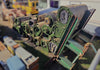 Multiple rolls of salvaged artificial turf stacked on a large green metal forklift attachment rack